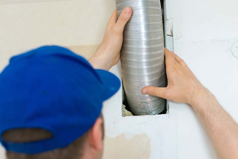 Blog Title: When Is It Time for a Split-System AC Replacement? Photo:Man setting up ventilation system indoors.