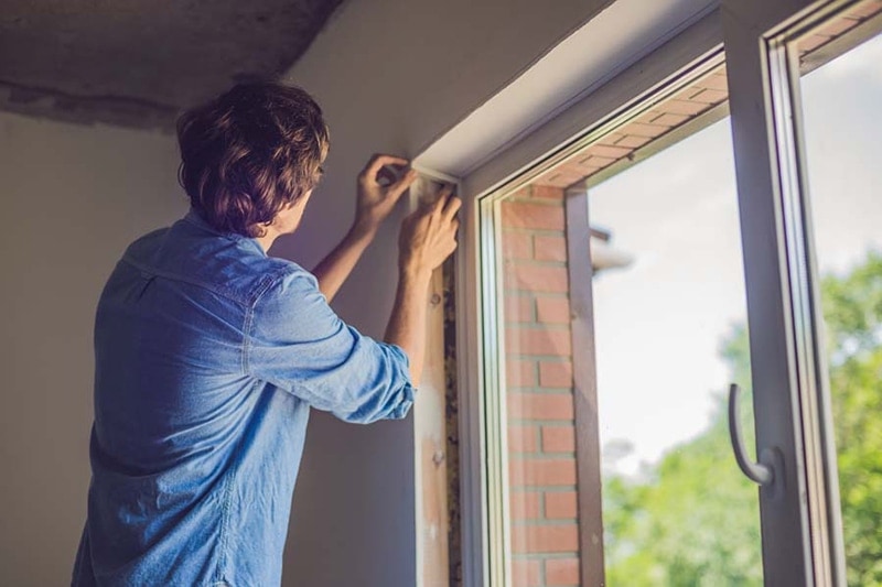 man sealing window