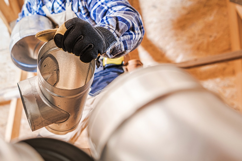 Close Up Of HVAC Worker Fitting Pipe Connections Of Air Ventilation System.