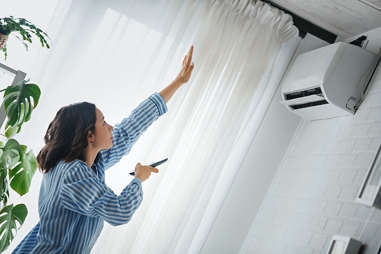 Blog Title: How your AC cools your home Photo: Woman turning on the air conditioner.