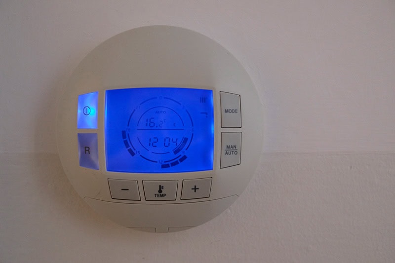 How to Set Your Programmable Thermostat. Photo of a digital thermostat mounted on a wall.