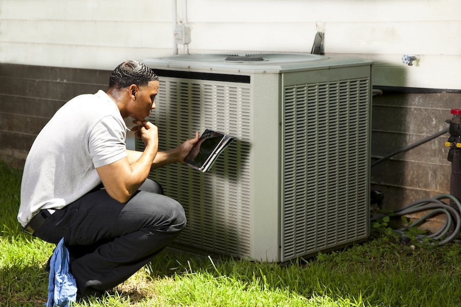 HVAC technician inspecting an air conditioner outside in Austin