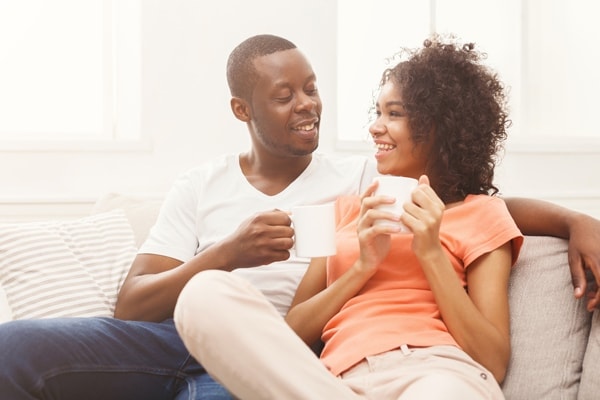 Happy african-american couple drinking coffee at cozy home. Family leisure and relaxation concept