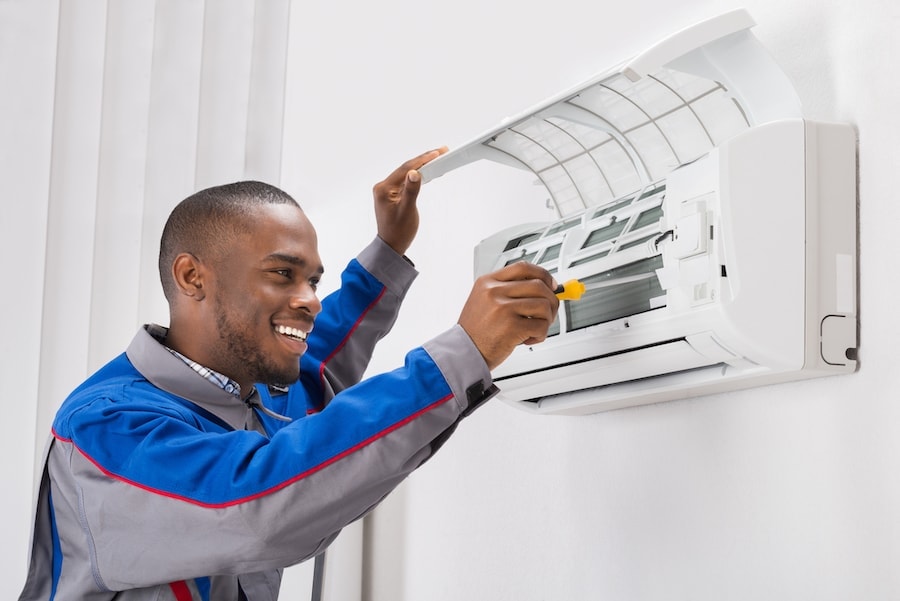 Happy Young African Male Technician Repairing Air Conditioner.