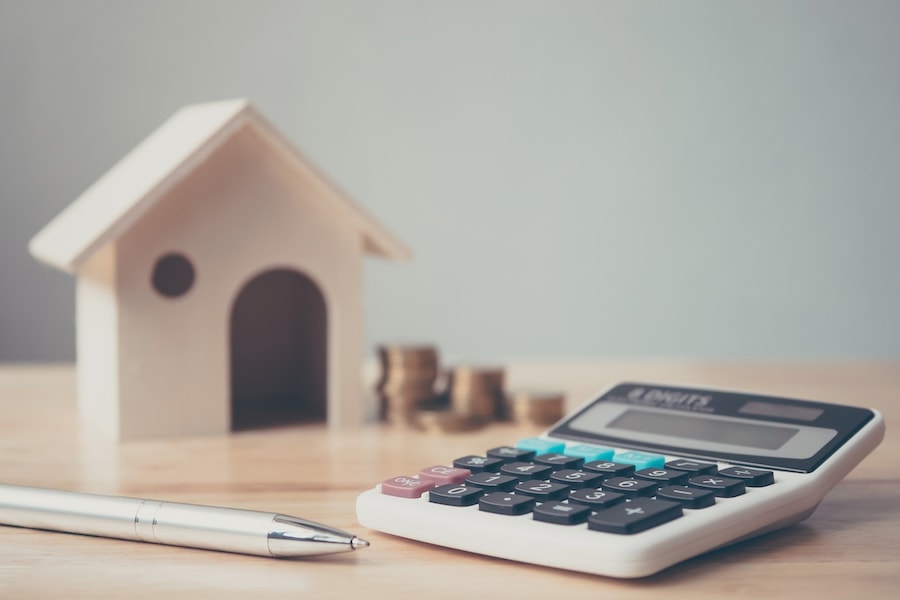 Close up of a calculator on a table with a small wooden house.