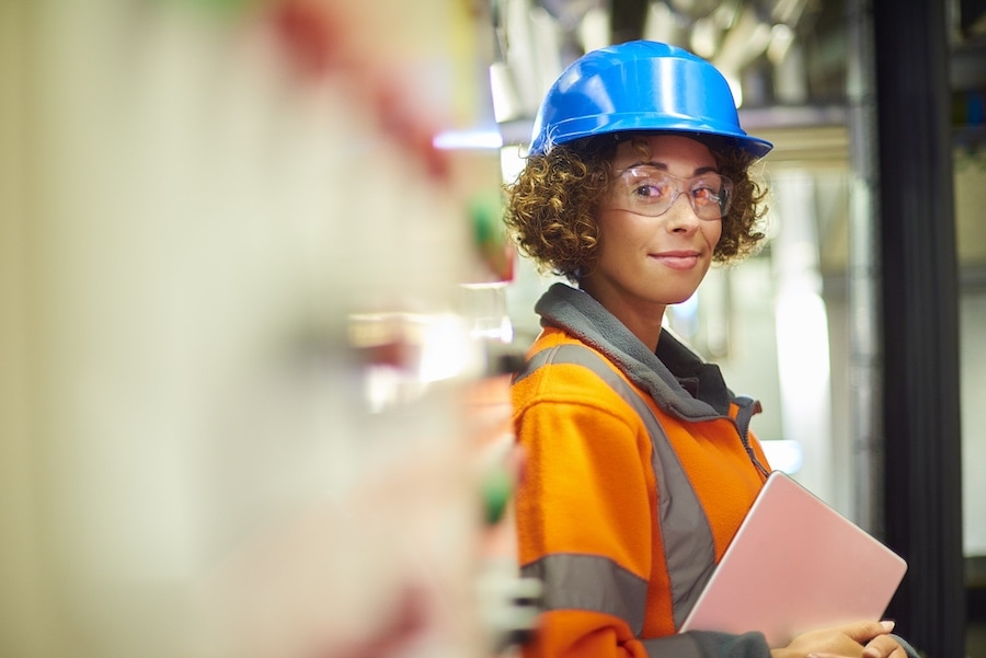 A female industrial service engineer has just conducted a safety check of a control panel in a boiler room. She is wearing hi vis