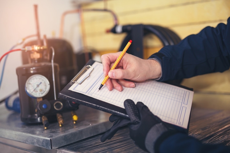 HVAC technician writing on paper on a clipboard.